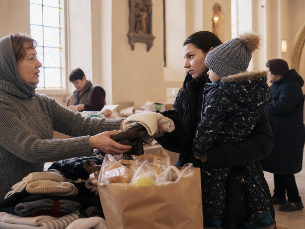 A mother holding a young child while receiving groceries and warm clothing